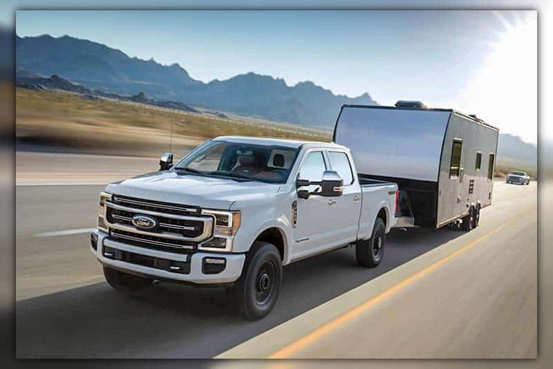 2023 Ford F-250 Super Duty towing a luxurious camper through a beautiful landscape.